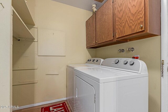 washroom with baseboards, cabinet space, and independent washer and dryer