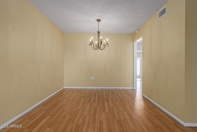 unfurnished room with visible vents, light wood-style flooring, a textured ceiling, and baseboards