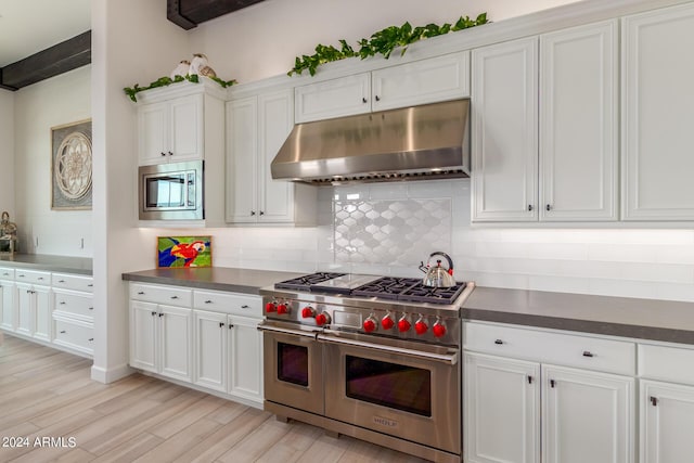 kitchen featuring decorative backsplash, white cabinetry, stainless steel appliances, and light wood-type flooring