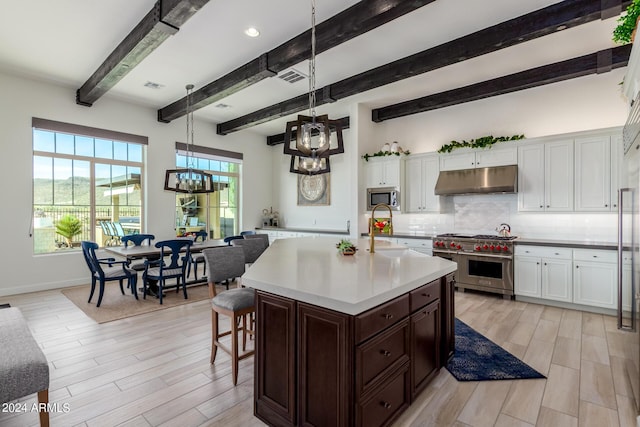 kitchen featuring pendant lighting, appliances with stainless steel finishes, a kitchen bar, sink, and a center island with sink