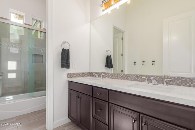 bathroom with bath / shower combo with glass door, backsplash, and vanity