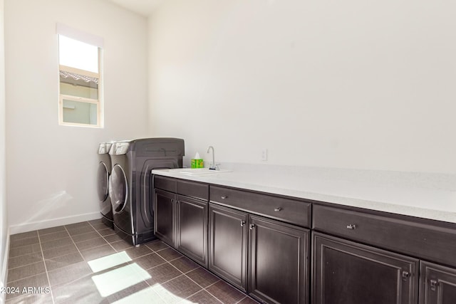 clothes washing area with cabinets, dark tile patterned flooring, washer and clothes dryer, and sink