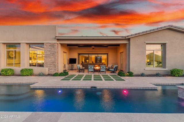 back house at dusk with an outdoor living space, ceiling fan, and a patio area