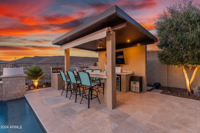 patio terrace at dusk featuring an outdoor bar and wine cooler