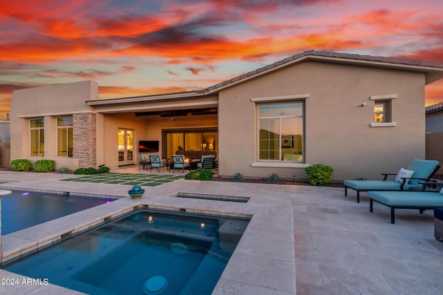 rear view of property with a pool with hot tub and a patio area