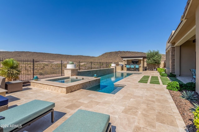 view of pool with an in ground hot tub, a bar, a mountain view, and a patio