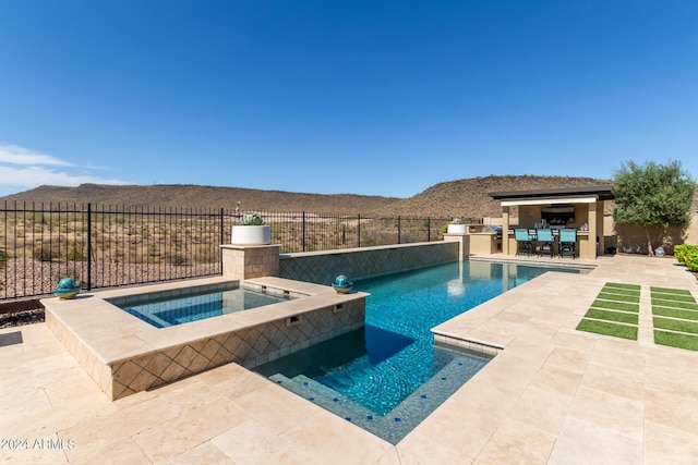 view of pool featuring an in ground hot tub, a patio area, an outdoor kitchen, and a mountain view