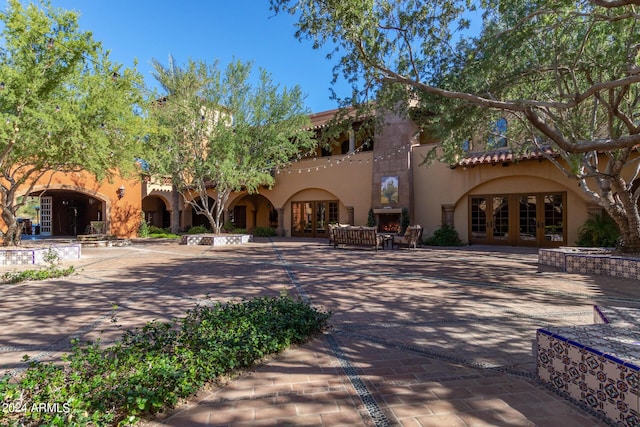 view of front facade featuring exterior fireplace, french doors, and a patio