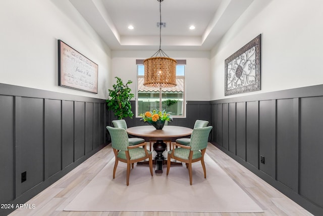 dining area with light hardwood / wood-style flooring and a raised ceiling