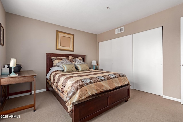 bedroom featuring a closet, visible vents, light carpet, and baseboards