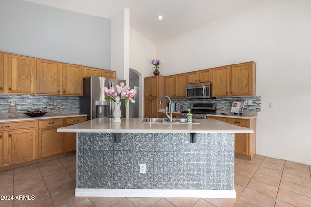 kitchen with decorative backsplash, stainless steel appliances, sink, high vaulted ceiling, and an island with sink