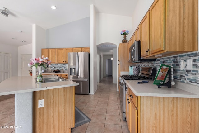 kitchen with sink, a center island, tasteful backsplash, vaulted ceiling, and appliances with stainless steel finishes