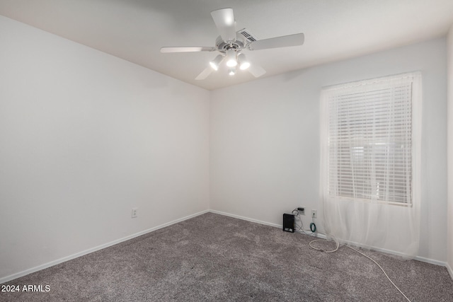 spare room featuring ceiling fan and dark carpet