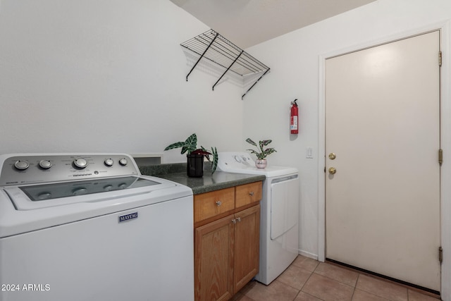 washroom with washer and dryer, cabinets, and light tile patterned floors