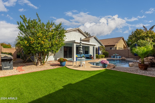 rear view of property featuring a lawn, a patio area, a fenced in pool, and an outdoor hangout area