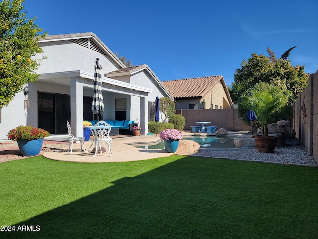 back of property with a fenced in pool, a patio area, outdoor lounge area, and a lawn