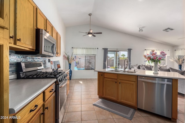 kitchen with lofted ceiling, sink, decorative backsplash, light tile patterned flooring, and stainless steel appliances