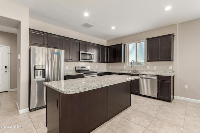 kitchen featuring appliances with stainless steel finishes, a center island, light tile patterned floors, and dark brown cabinets