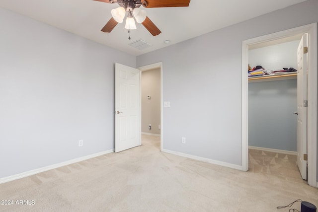 unfurnished bedroom featuring a spacious closet, ceiling fan, a closet, and light colored carpet