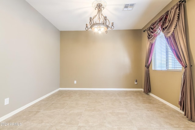 unfurnished room with a chandelier and light tile patterned floors