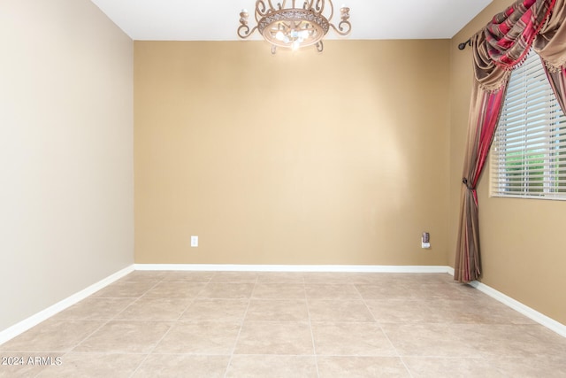 empty room with light tile patterned floors and a chandelier