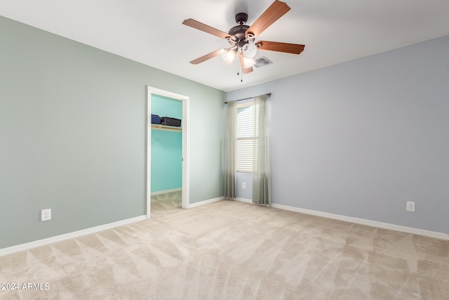 empty room featuring ceiling fan and light carpet