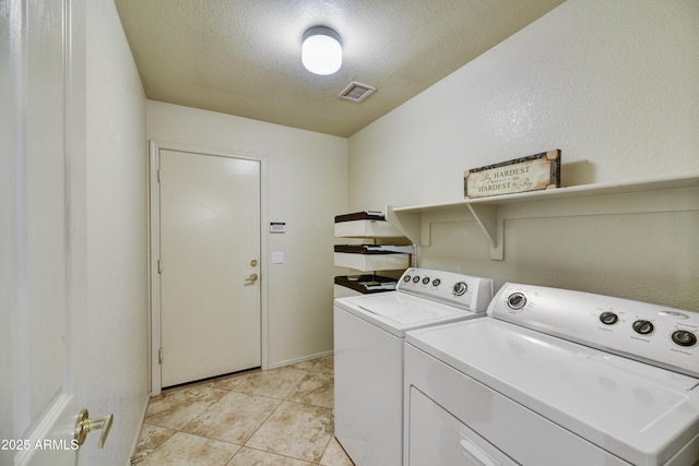 laundry area featuring a textured ceiling, light tile patterned flooring, visible vents, washer and clothes dryer, and laundry area