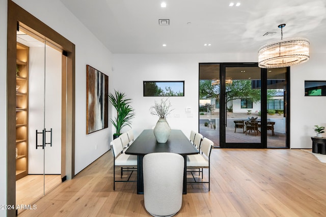 dining space featuring light wood-type flooring and an inviting chandelier