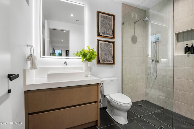 bathroom with a tile shower, tile patterned flooring, vanity, and toilet