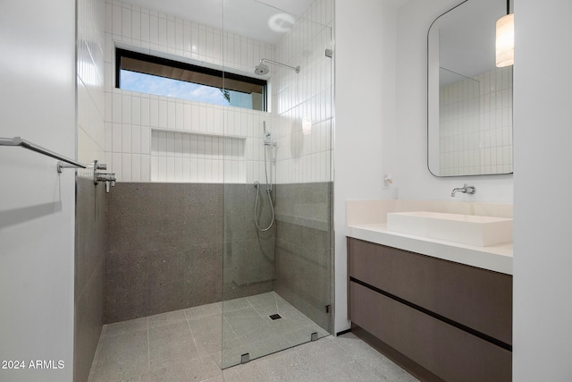 bathroom with a tile shower and vanity