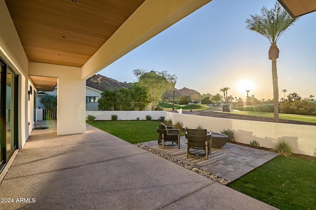 patio terrace at dusk featuring a lawn