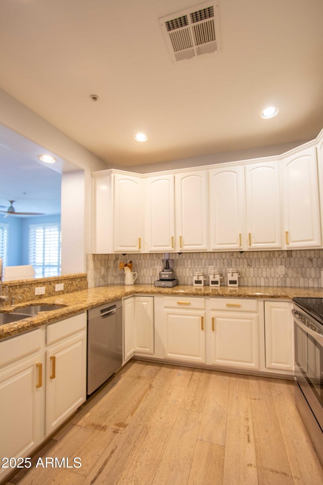 10655 N 9th St Unit 112, Phoenix, AZ 85020 - kitchen featuring appliances with stainless steel finishes, light wood-style flooring, light stone counters, white cabinets, and recessed lighting