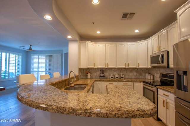 10655 N 9th St Unit 112, Phoenix, AZ 85020 - kitchen featuring stainless steel appliances, a peninsula, recessed lighting, light stone countertops, and backsplash