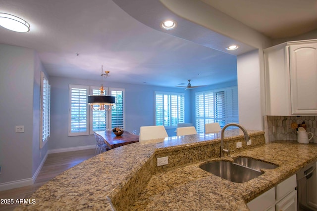 10655 N 9th St Unit 112, Phoenix, AZ 85020 - kitchen with dishwasher, recessed lighting, light stone counters, white cabinets, and a peninsula