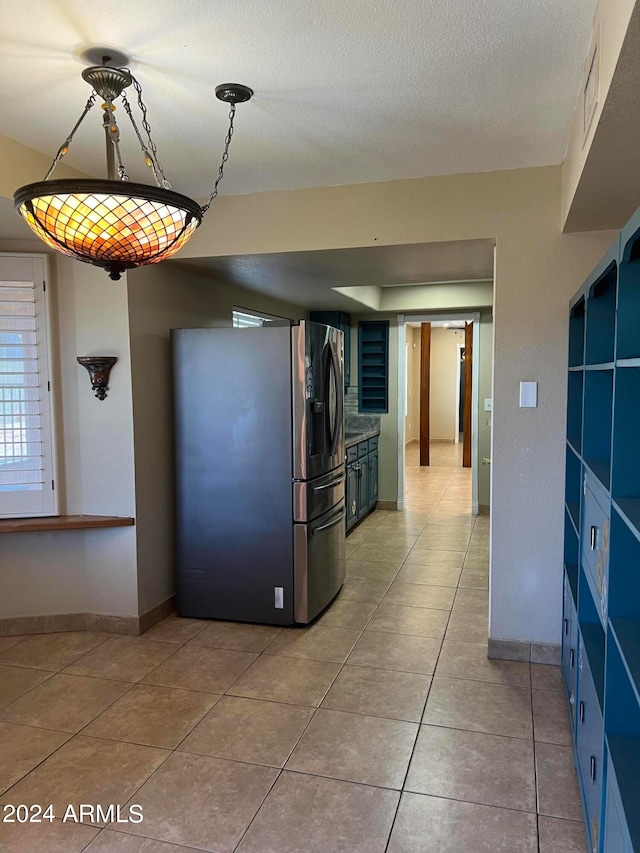 kitchen featuring light tile patterned flooring, blue cabinets, stainless steel fridge with ice dispenser, and a textured ceiling