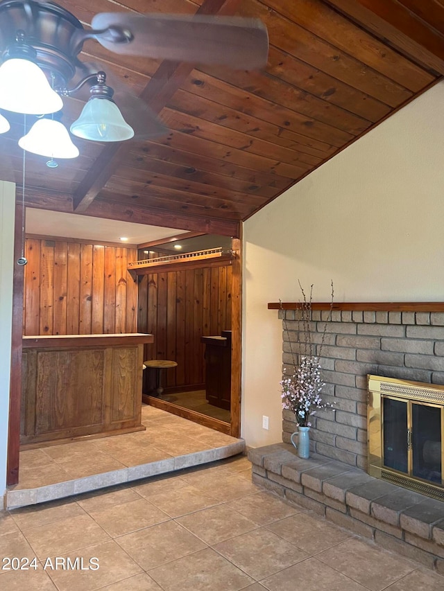 interior space featuring wood walls, wood ceiling, lofted ceiling with beams, a brick fireplace, and tile patterned flooring