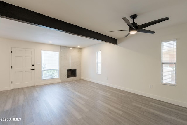 6544 N 7th Ave Unit 14, Phoenix, AZ 85013 - unfurnished living room featuring a high end fireplace, wood finished floors, beam ceiling, healthy amount of natural light, and recessed lighting
