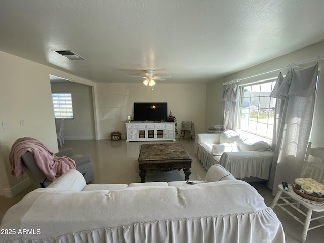 living room with visible vents, plenty of natural light, a textured ceiling, and ceiling fan