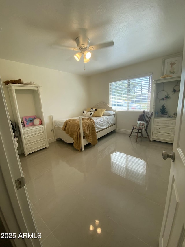 tiled bedroom with a ceiling fan, a textured ceiling, and baseboards