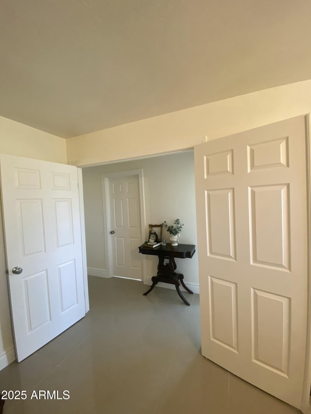 corridor featuring tile patterned flooring and baseboards