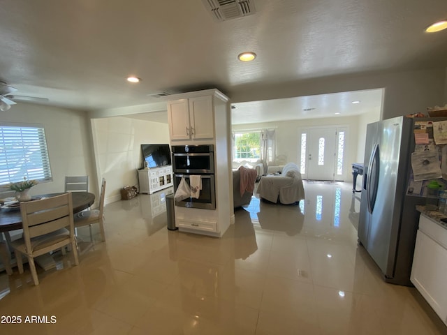 kitchen featuring stainless steel appliances, white cabinets, visible vents, and open floor plan