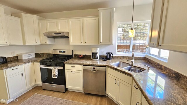1520 W Encanto Blvd, Phoenix, AZ 85007 - kitchen with under cabinet range hood, a sink, light wood-style flooring, appliances with stainless steel finishes, and white cabinetry