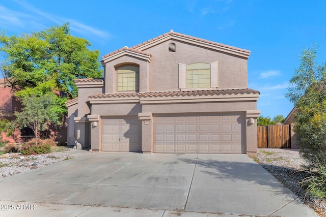 mediterranean / spanish-style home with a tiled roof, fence, concrete driveway, and stucco siding