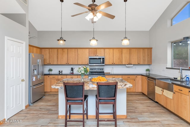 kitchen with high vaulted ceiling, appliances with stainless steel finishes, light wood finished floors, and a sink