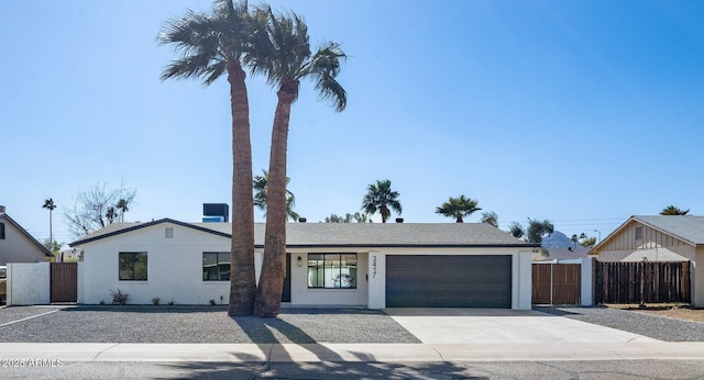 view of front facade featuring stucco siding, an attached garage, concrete driveway, and fence