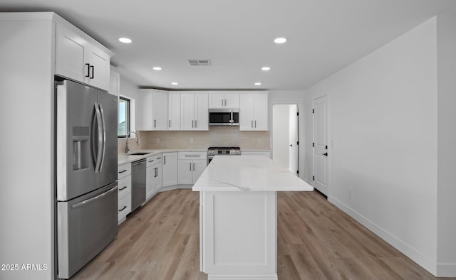 kitchen with visible vents, a sink, a kitchen island, appliances with stainless steel finishes, and decorative backsplash