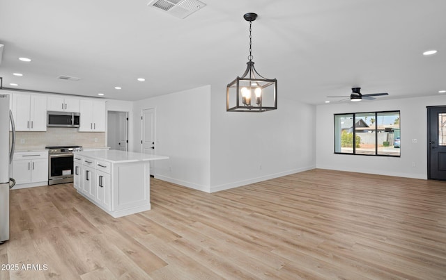 kitchen with visible vents, backsplash, light wood-style flooring, appliances with stainless steel finishes, and white cabinetry