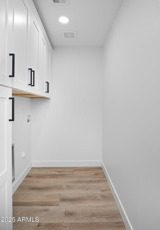 washroom featuring light wood-type flooring, visible vents, washer hookup, cabinet space, and baseboards