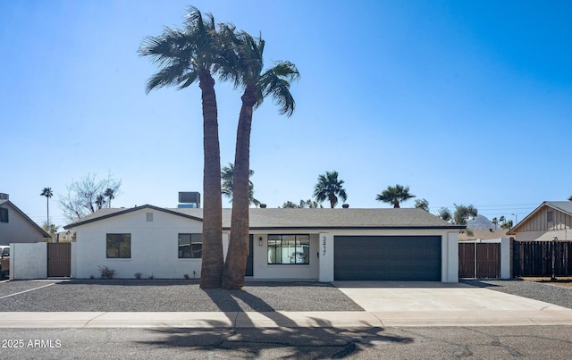 ranch-style home with a garage, concrete driveway, stucco siding, and fence