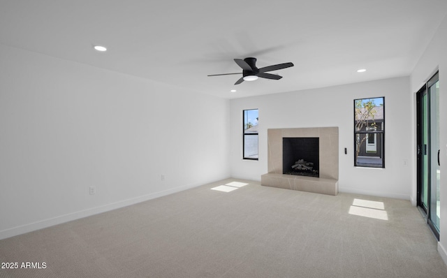 unfurnished living room featuring baseboards, carpet floors, recessed lighting, ceiling fan, and a tiled fireplace